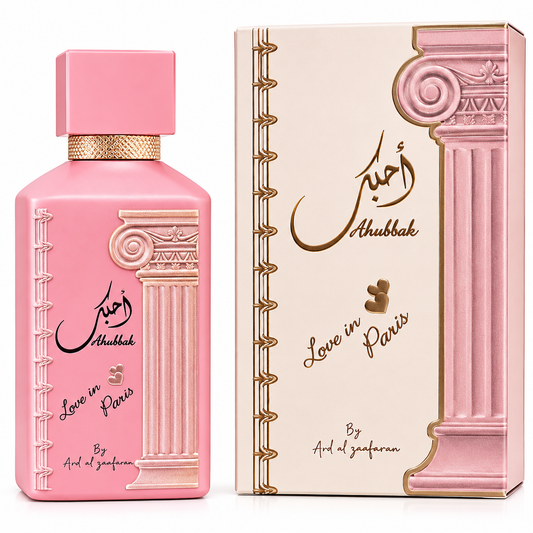 Pink perfume bottle with a matching pink and beige box, both decorated with gold classical column illustrations and Arabic script reading 'Ahbbak' and 'Love in Paris' by Arsl al Zafaran.
