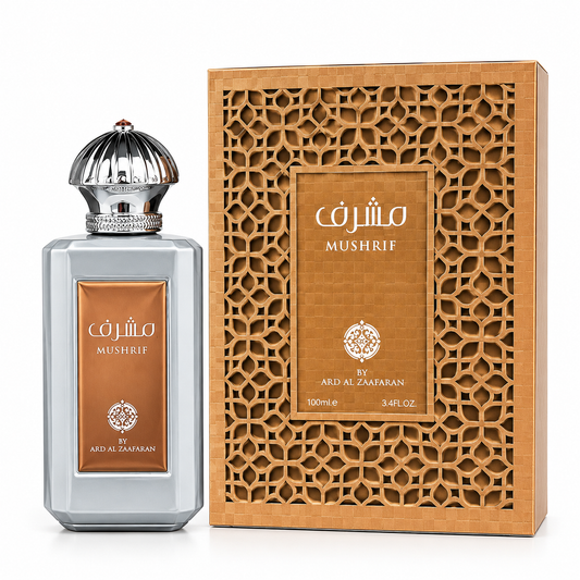 A bottle of Mushrif perfume next to its ornate wooden box. The bottle has a silver-gray glass body with a metallic silver cap and a bronze-brown label.
